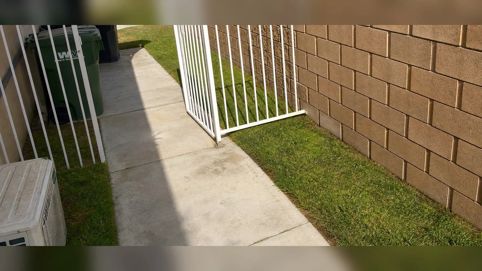 Lancaster side yard after cleanup with the walkway swept and the wall and gate left intact.