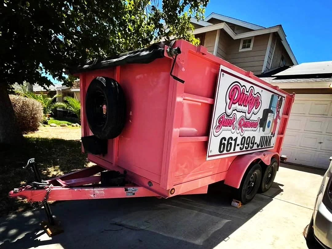 Pinky's branded pink junk-removal trailer parked in a residential driveway in the Antelope Valley.