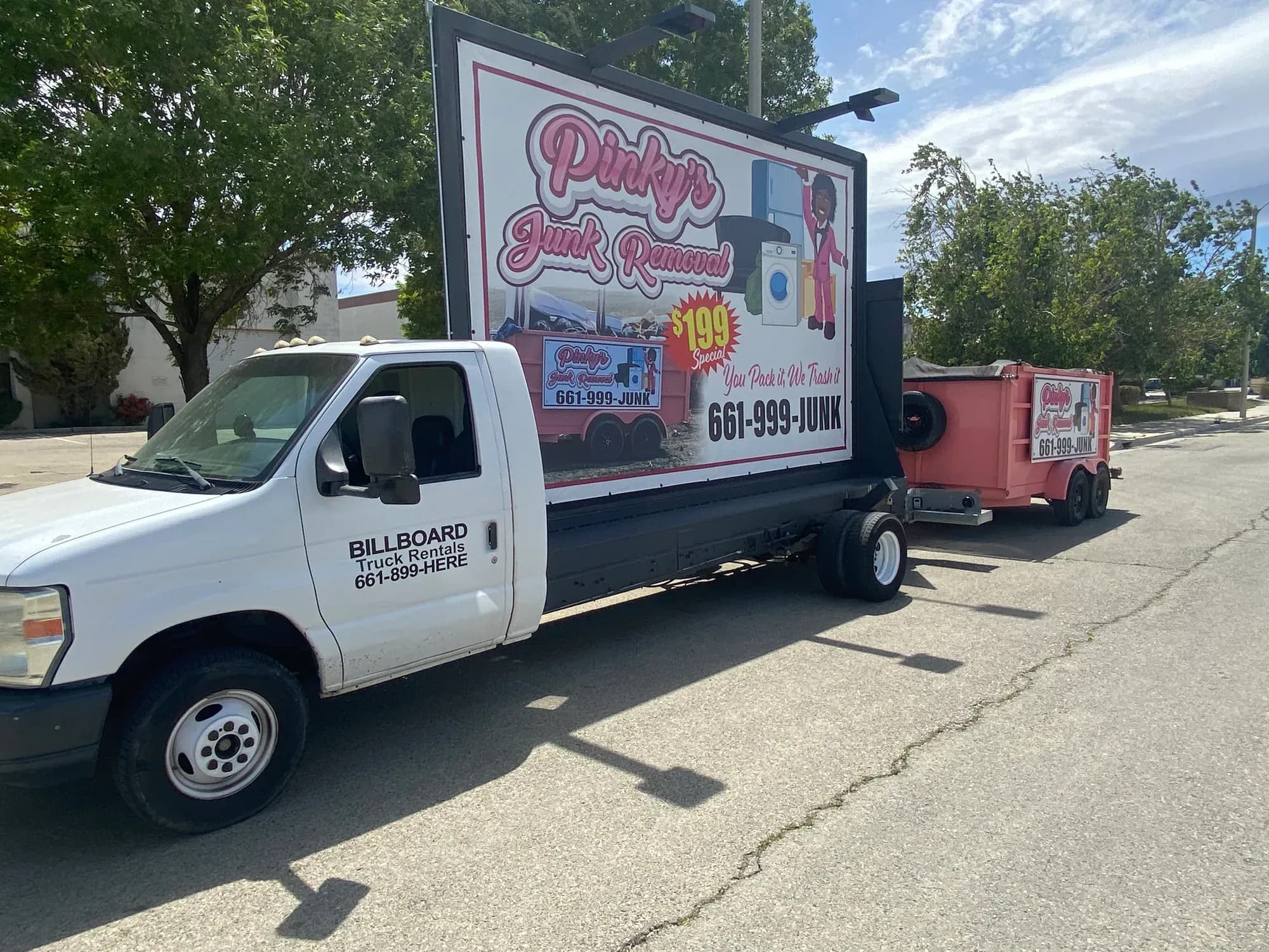 Pinky's billboard truck parked with the bright pink junk-removal trailer attached.